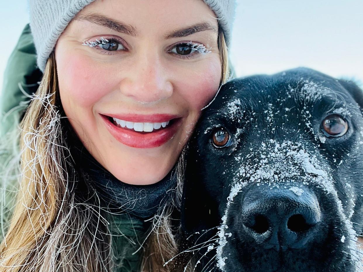 hilary posing with her black dog in the snow in canada