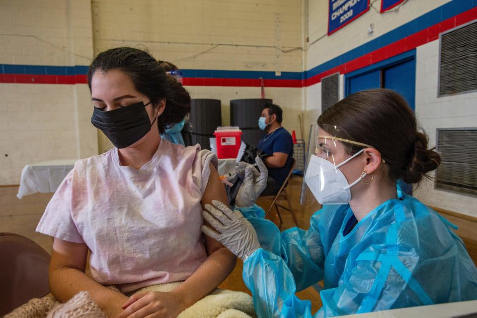 Angelica Romero, 30, is inoculated with the Moderna Vaccine for Covid-19 by pharmacy student Kayla Sepe at Central Falls High School in Central Falls, Rhode Island, on February 13, 2021. - The city of Central Falls is currently offering Covid-19 vaccinations to any adult 18 years and older in contrast to the rest of the state which is following state guidelines and offering only to certain groups, frontline workers and people 75 years old and older. According to the US Census bureau, Central Falls is made up of over 66% Hispanic and almost 13% Black residents. 