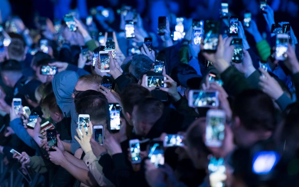 Spectators filming through their mobile phones at an event in Cardiff - Getty 