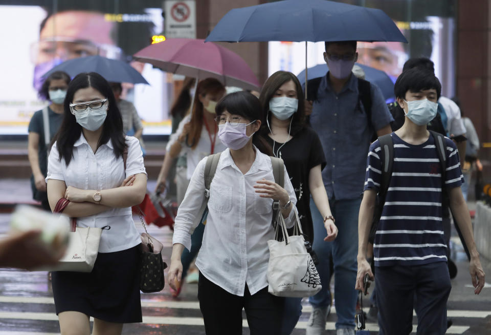 People wearing face masks to protect against the spread of the coronavirus walk in the light rain from approaching Typhoon In-Fa in Taipei, Taiwan, Thursday, July 22, 2021. (AP Photo/Chiang Ying-ying)