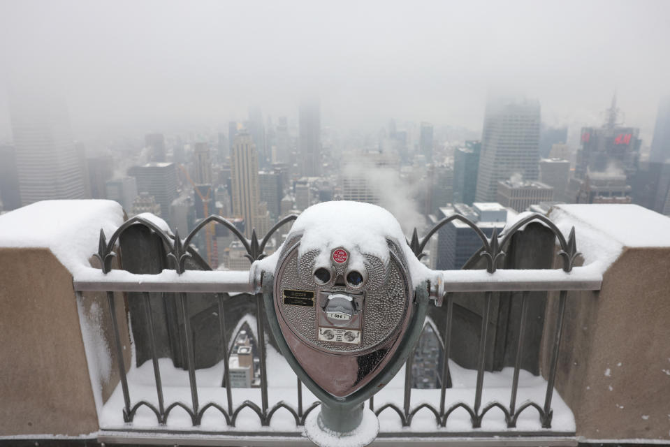 Snow sits on viewing binoculars at the Top of The Rock observation deck.