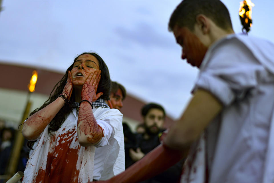 A woman covers her face with blood to take part in the Momotxorros carnival, in Alsasua, northern Spain, Tuesday, Feb. 21, 2023. (AP Photo/Alvaro Barrientos)