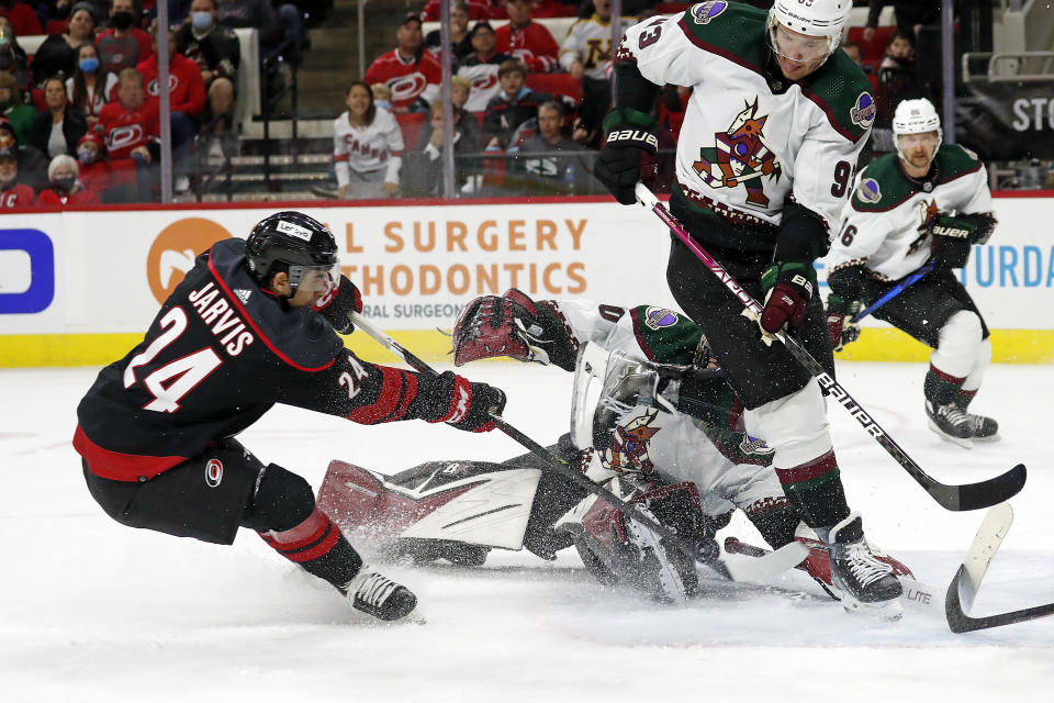 Carolina Hurricanes' Seth Jarvis (24) has his shot blocked by Arizona Coyotes' Dmitrij Jaskin (93) and goaltender Karel Vejmelka (70) during the second period of an NHL hockey game in Raleigh, N.C., Sunday, Oct. 31, 2021. (AP Photo/Karl B DeBlaker)