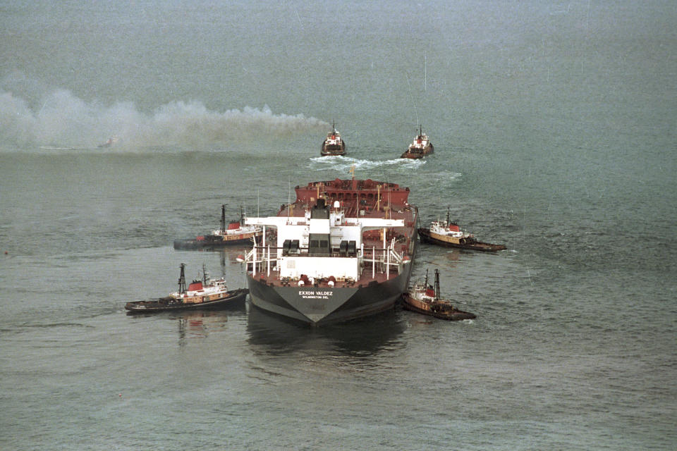 FILE - Tug boats, with smoke pouring from their stacks, pull the tanker Exxon Valdez from a reef in Prince William Sound, Alaska, on April 5, 1989. Jack Smith, an AP photographer who captured unforgettable shots of the eruption of Mount St. Helens, the Exxon-Valdez oil spill, the Olympics and many other events during his 35-year career with the news organization, passed away on Jan. 4, 2023, at his home in La Mesa, Calif. He was 80. (AP Photo/Jack Smith, File)