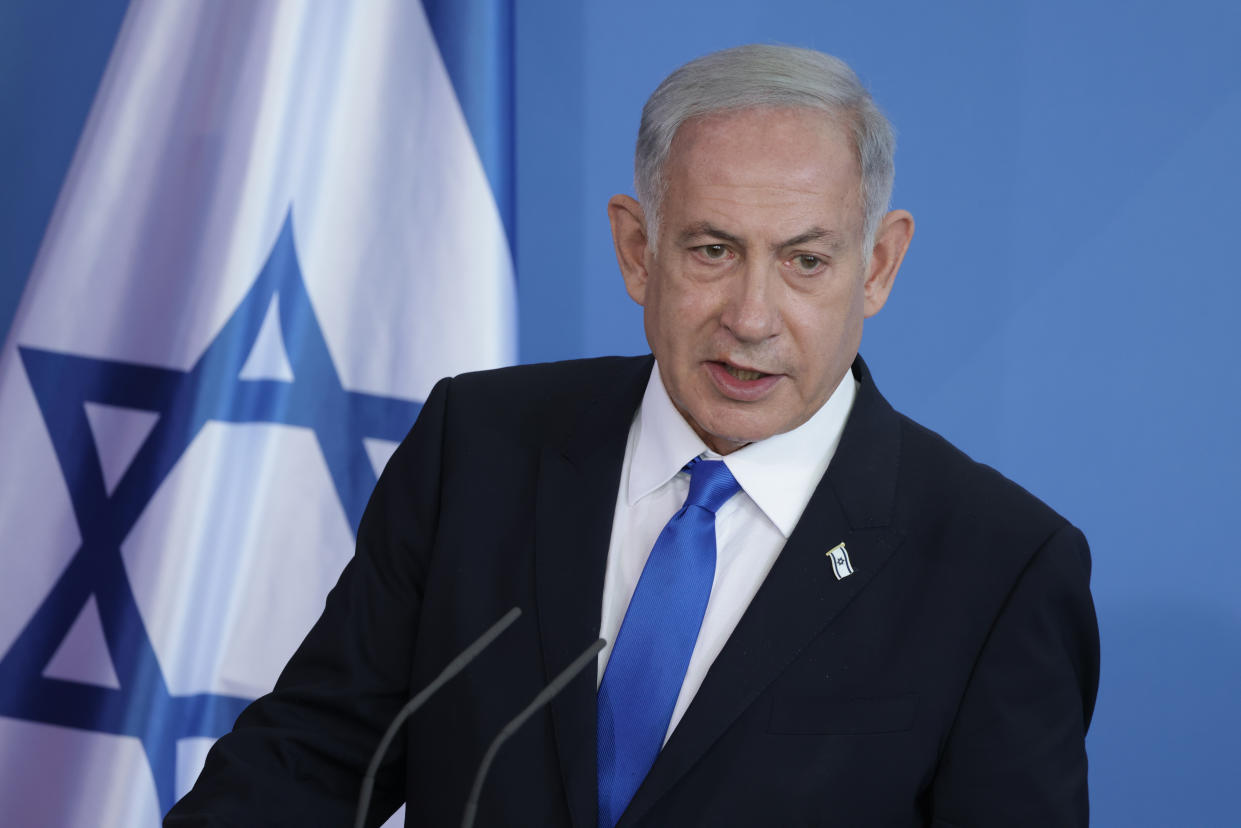 Israeli Prime Minister Benjamin Netanyahu stands at a microphone.