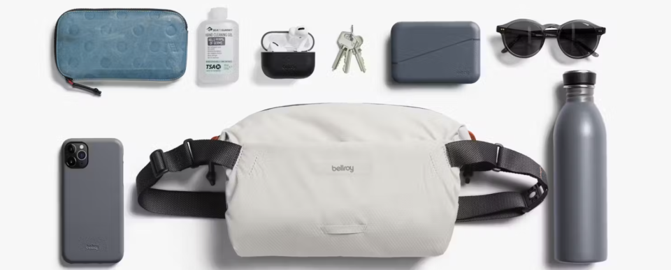 Bellroy Lite Sling in white and pictured with keys, sunglasses, smartphone, sanitizer.