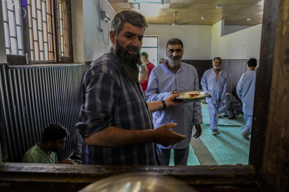 A staff member of a mental health hospital serves lunch to patients inside a mental health hospital in Srinagar, Indian controlled Kashmir, Tuesday, Aug 1, 2023. Kashmir's mental healthcare clinics depict invisible scars of decades of violent armed insurrections, brutal counterinsurgency, unparalleled militarization, unfulfilled demands for self-determination have fueled depression and drugs in the disputed region, experts say. (AP Photo/Mukhtar Khan)