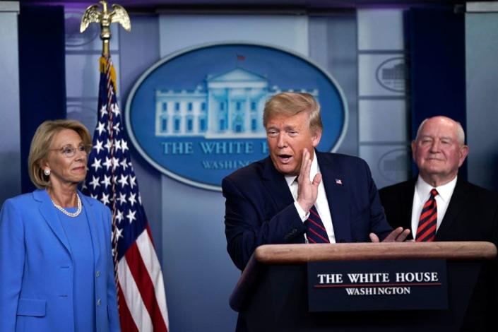 <div class="inline-image__caption"><p>Trump speaks as Secretary of Education Betsy DeVos and Secretary of Agriculture Sonny Perdue look on during a briefing on the coronavirus pandemic in the press briefing room of the White House on March 27, 2020, in Washington, D.C.</p></div> <div class="inline-image__credit">Drew Angerer/Getty</div>