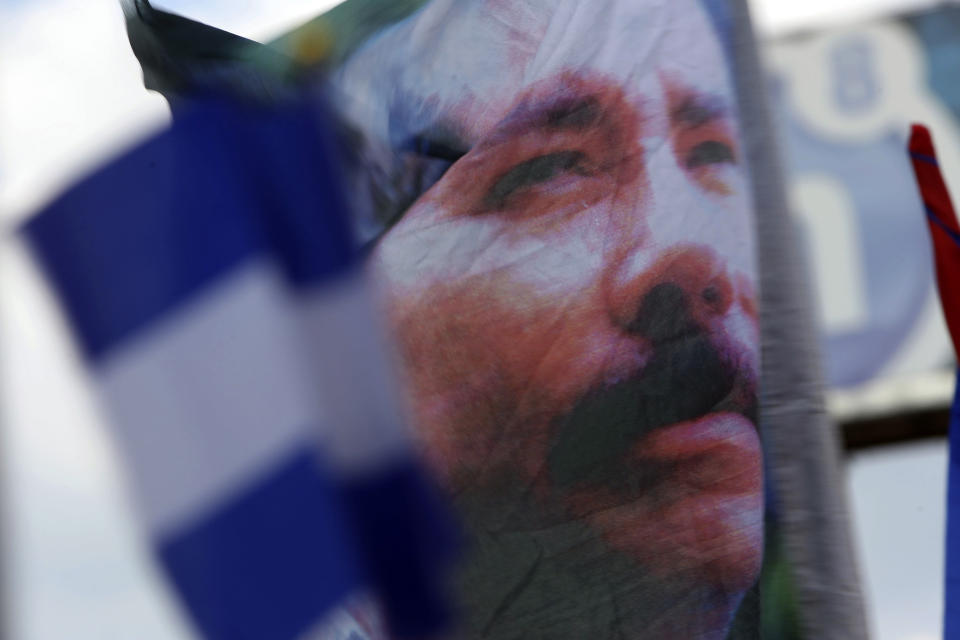 FILE - A banner emblazoned with an image of Nicaragua's President Daniel Ortega is waved by a supporter in Managua, Nicaragua, April 30, 2018. Ortega has forced hundreds of opposition figures into exile, stripping them of their citizenship, seizing their properties and declaring them “traitors of the homeland.” (AP Photo/Alfredo Zuniga, File)