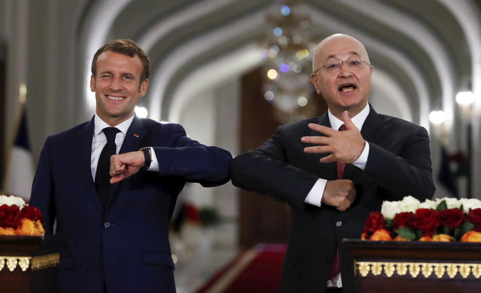 Iraqi President Barham Salih, right, and French President Emmanuel Macron greet each other with an elbow bump during a joint press conference at the Salam Palace Wednesday, Sept. 2, 2020 in Baghdad. French President Emmanuel Macron is the first head of state to visit the Iraqi capital since Prime Minister Mustafa al-Kadhimi, Iraq's former intelligence chief, formed a new government in May. (Gonzalo Fuentes/Pool via AP)