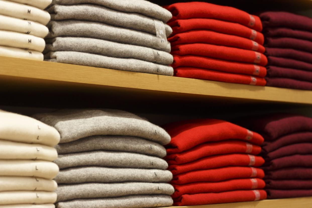 Piles of multicolored clothes on the shelves in store