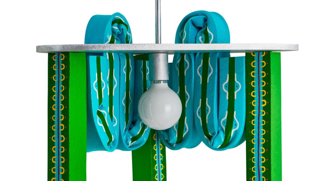 green and blue design pendant light that looks like it is a suspended vanity with large bulb at center and three legs