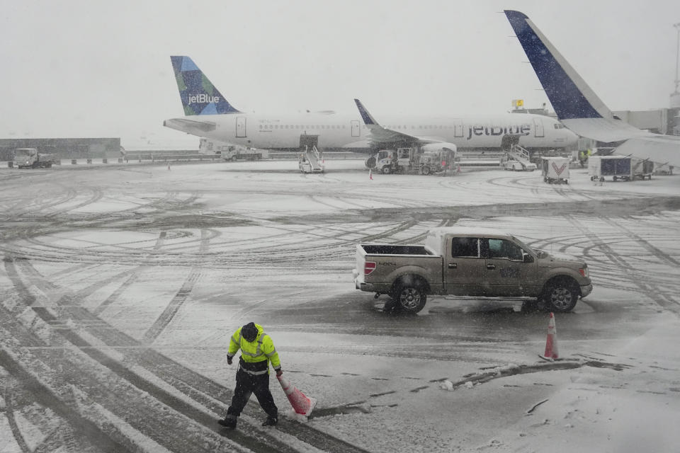 A man sets cones near planes as snow falls at John F. Kennedy International Airport Tuesday, Feb. 13, 2024, in New York. (AP Photo/Frank Franklin II)