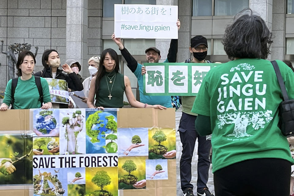 People gather in front of the Tokyo Metropolitan Government Building in Tokyo, Sunday, April 9, 2023, as they protest against the Meiji Jingu Gaien area redevelopment project. An area known as Jingu Gaien is famous for a row of about 150 ginko trees. The redevelopment plans call for razing a historic baseball stadium and a neighboring rugby stadium in the area and rebuilding them in different spots in the reconfigured space, making room for a pair of towering skyscrapers and a shopping area. (AP Photo/Stephen Wade)