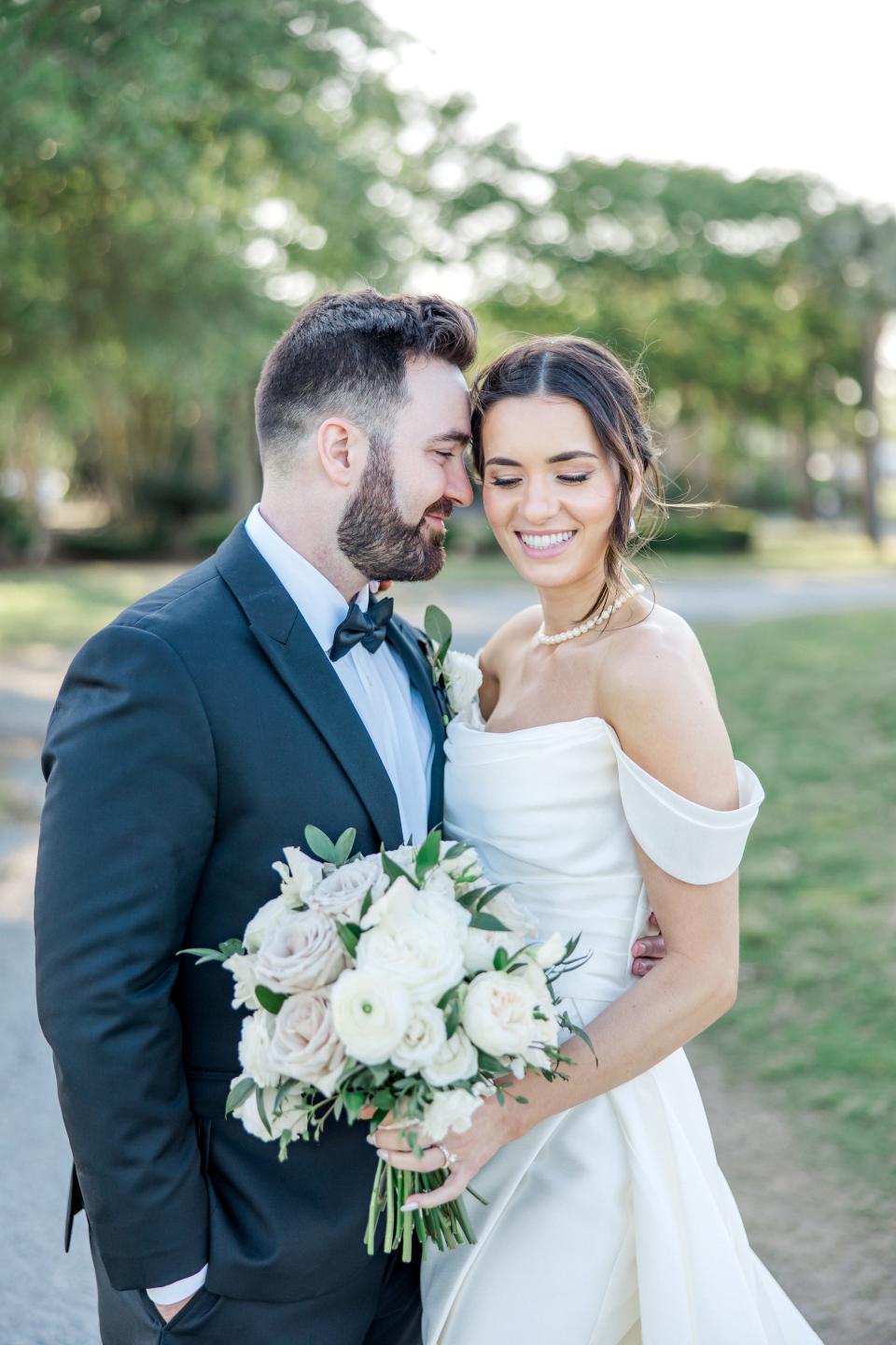 A bride and groom lean their heads together and smile.