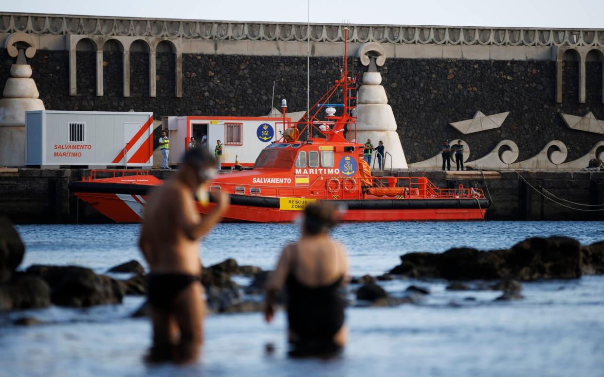 A rescue boat can be seen on the harbour wall as holidaymakers enjoy the water at La Restinga on El Hierro