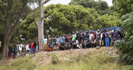 Foreigners look on as people board a bus for Zimbabwe from a camp for those affected by anti-immigrant violence in Chatsworth, north of Durban April 19, 2015. REUTERS/Rogan Ward