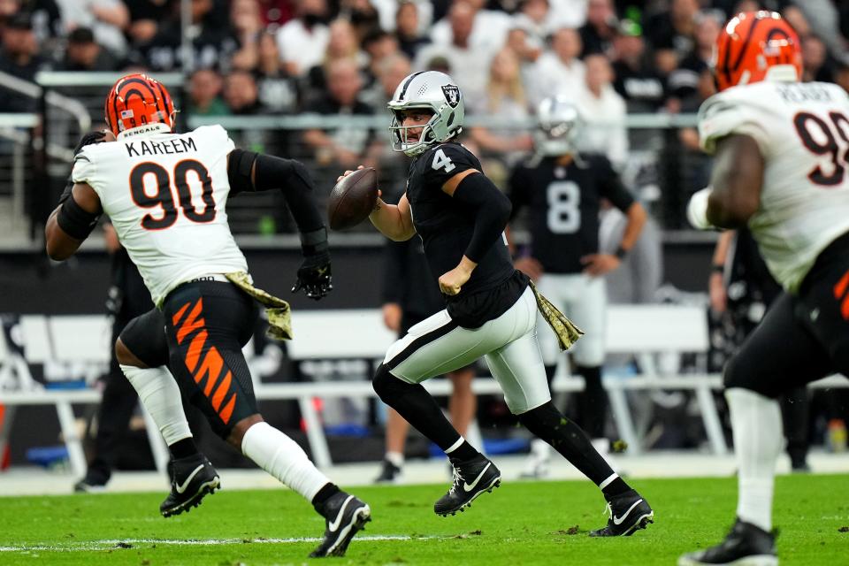 Las Vegas Raiders quarterback Derek Carr (4) rolls out of the pocket as Cincinnati Bengals defensive end Khalid Kareem (90) gives chase in the second quarter during a NFL Week 11 game, Sunday, Nov. 21, 2021, at Allegiant Stadium in Las Vegas.