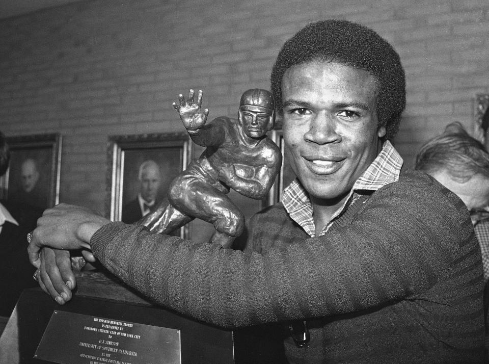 FILE - Southern California tailback Charles White puts his arms around the Heisman Trophy won by O.J. Simpson in 1968 after White was announced as the winner of the 1979 Heisman Trophy, Dec. 3, 1979, in Los Angeles. White died Wednesday, Jan. 11, 2023. He was 64. USC announced the death of White, who is still the Trojans' career rushing leader with 6,245 yards. The nine-year NFL veteran died of cancer, the school said. (AP Photo/Wally Fong, File)