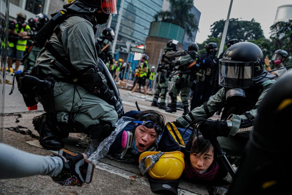 Police officers in riot gear pin down protesters