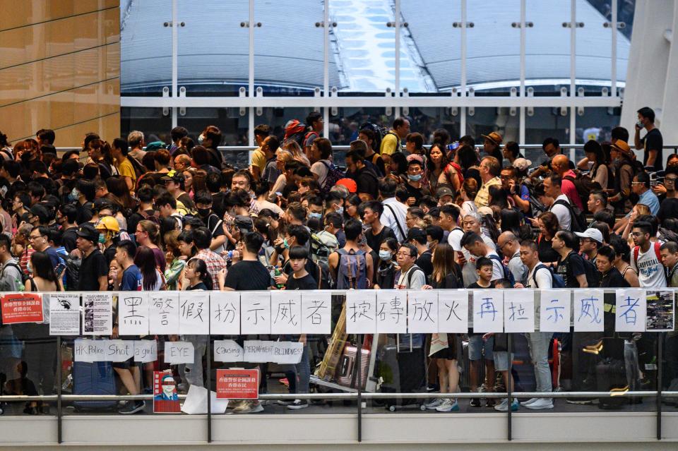 Protesters line up for a train at an airport station after a protest.