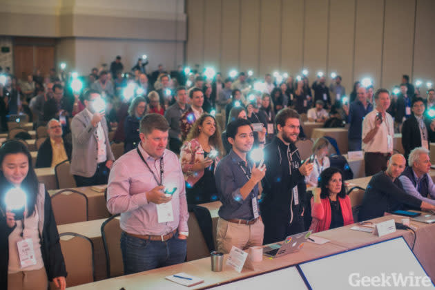 GeekWire Summit attendees in Seattle hold up their smartphones as a message arrives from the federal government testing an emergency alert system. (GeekWire Photo / Dan DeLong) <a href="https://www.geekwire.com/2018/test-president-trump-messages-millions-using-emergency-alert-system/" rel="nofollow noopener" target="_blank" data-ylk="slk:Read the story.;elm:context_link;itc:0;sec:content-canvas" class="link "><strong>Read the story.</strong></a>