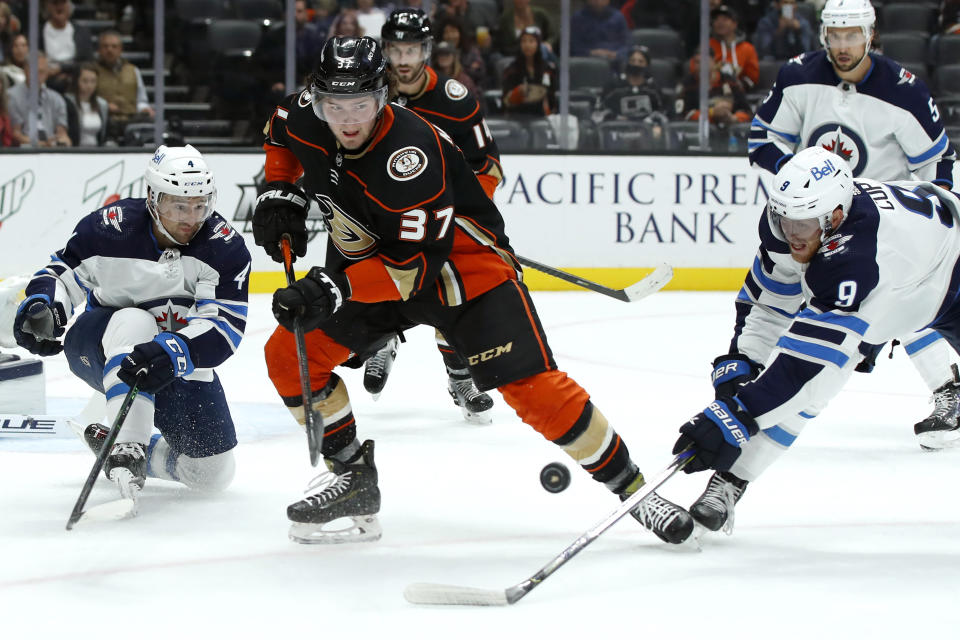 Anaheim Ducks center Mason McTavish (37) and Winnipeg Jets center Andrew Copp (9) work for the puck with defenseman Neal Pionk (4) watching during the second period of an NHL hockey game in Anaheim, Calif., Wednesday, Oct. 13, 2021. (AP Photo/Alex Gallardo)