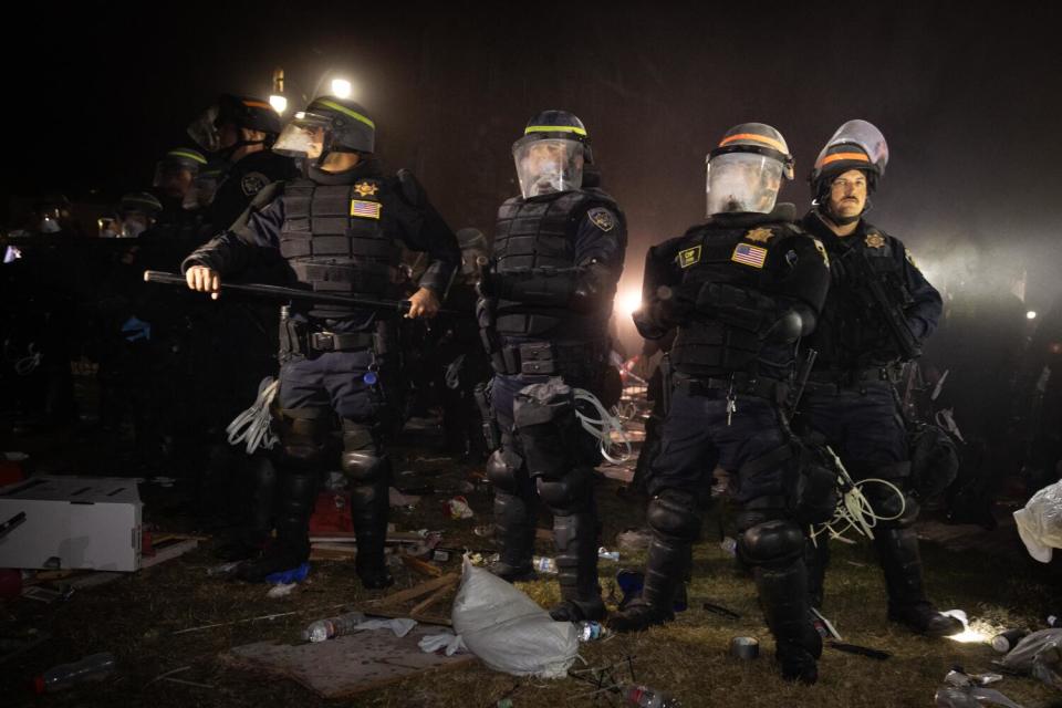 Authorities in riot gear breach and break up a the pro-Palestinian encampment at UCLA at night.