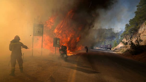 PHOTO: A firefighter tries to extinguish the flames next to motorcycles during a wildfire near Megara, Greece, July 20, 2022. (Petros Giannakouris/AP)