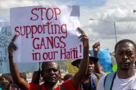 FILE - In this Dec. 10, 2020 file photo, a protester holds up a sign with a message to stop gang violence during a protest demanding the resignation of Haiti's President Jovenel Moise, in Port-au-Prince, Haiti. Human rights group Fondasyon Je Klere says more than 150 gangs operate in Haiti, some dedicated to kidnapping. (AP Photo/Dieu Nalio Chery, File)