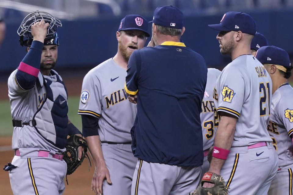 Milwaukee Brewers relief pitcher Drew Rasmussen, second from left, talks to pitching coach Chris Hook on the mound during the tenth inning of a baseball game against the Miami Marlins, Sunday, May 9, 2021, in Miami. (AP Photo/Marta Lavandier)