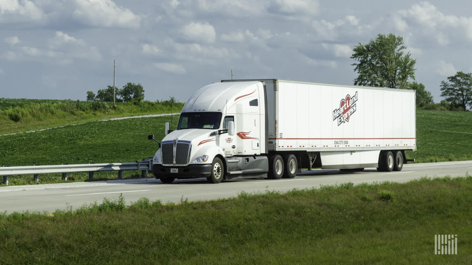 A white Heartland tractor pulling a white Heartland dry van trailer