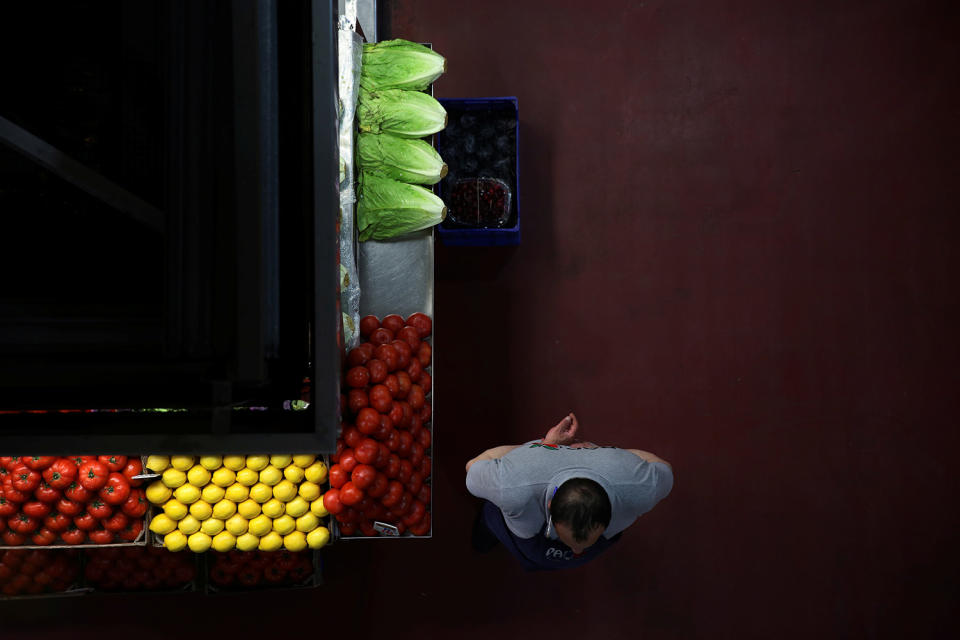 A grocer waits for customers at a food market in Madrid