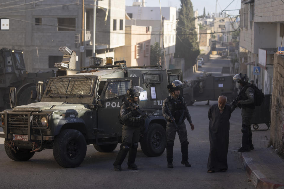 An elderly Palestinian man is sent back by Israeli border police, that secures the parameter while army forces blow up the family house of Palestinian Yahia Merai in the West Bank town of Qarawat Bani Hassan, Salfit, Tuesday, July 26, 2022. Israeli soldiers demolished the residences of Palestinian attackers Yahia Merai and Youssef Assi who committed the deadly attack in the Israeli settlement of Ariel in April 2022, the Israeli army said. (AP Photo/Nasser Nasser)