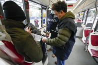 Carabinieri policemen check the green health pass of public transportation passengers in Rome, Monday, Dec. 6, 2021, on the first day a super green health pass went into effect. Italian police can check whether diners in restaurants or bars have a "super" green health pass certifying that they are either vaccinated or have recently recovered from the virus. (AP Photo/Andrew Medichini)