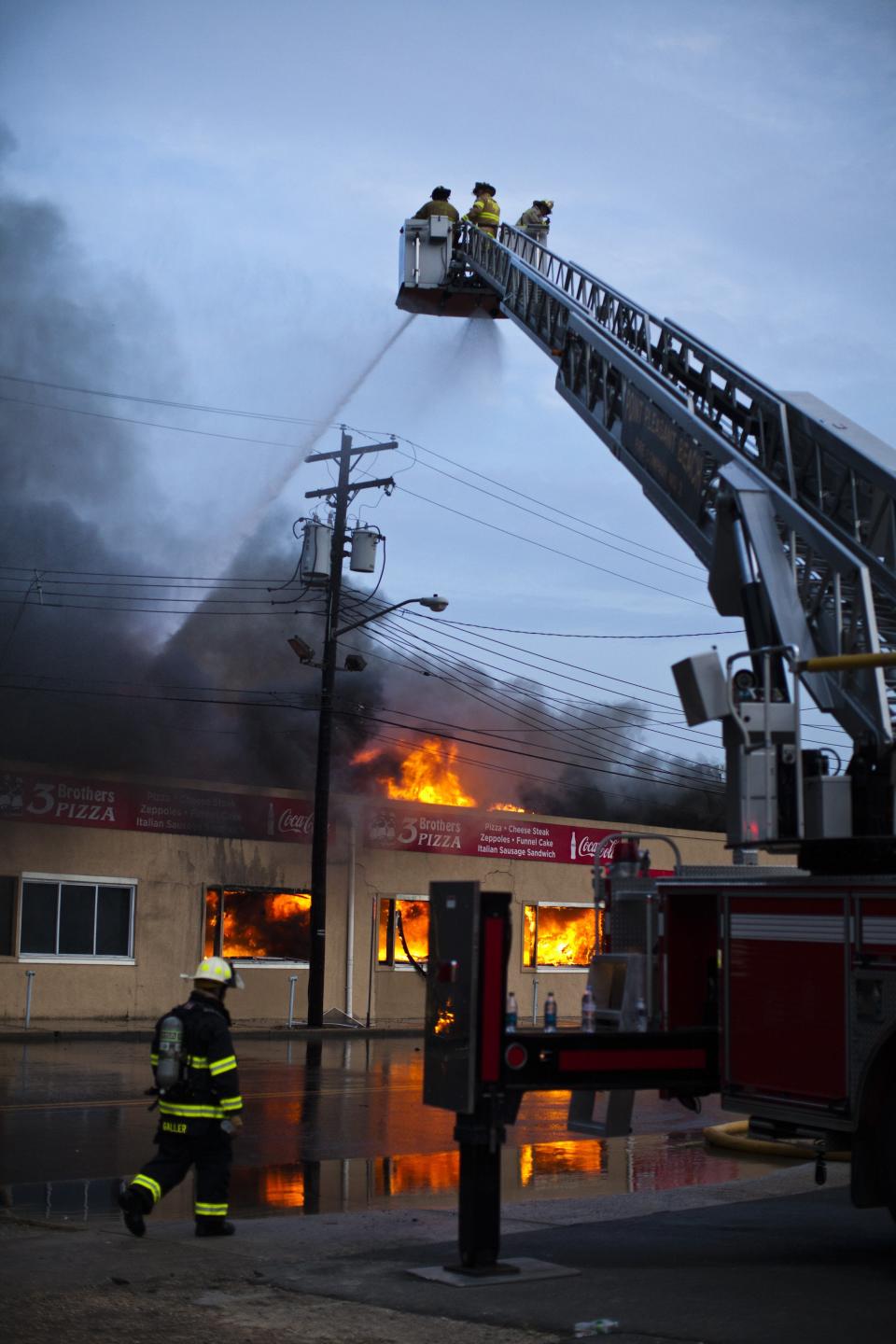 New Jersey firefighters spray water as they try to control a massive fire in Seaside Park in New Jersey September 12, 2013. The fast-moving fire that started in a custard shop raged through several blocks of boardwalk and businesses on Thursday in Seaside Park, a shore town that was still rebuilding from damage caused by Superstorm Sandy. (REUTERS/Eduardo Munoz)