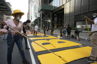 Azia Toussaint, left, participates in the painting of Black Lives Matter on Fifth Avenue in front of Trump Tower, Thursday, July 9, 2020, in New York. (AP Photo/Mark Lennihan)