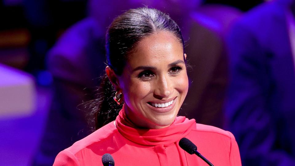 Meghan Markle smiling in a red outfit