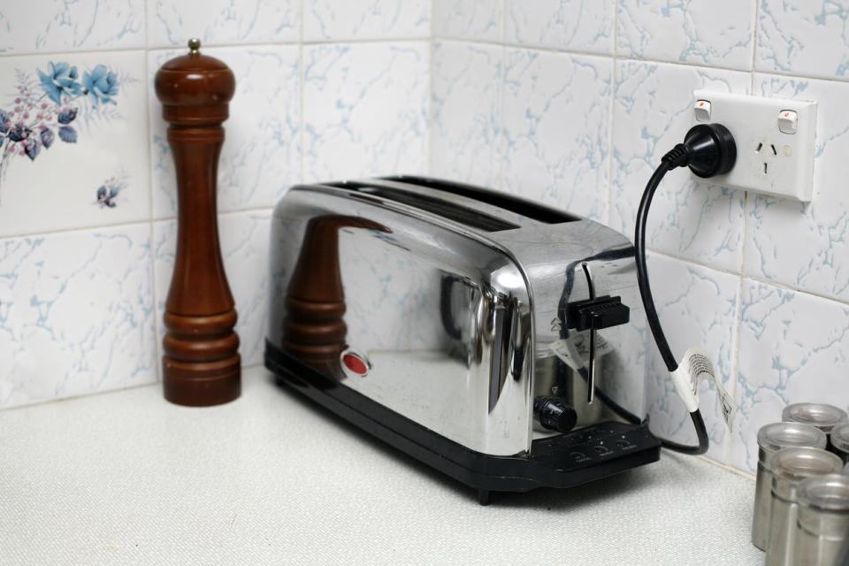 chrome toaster in corner of kitchen counter plugged into outlet with tiled backsplash