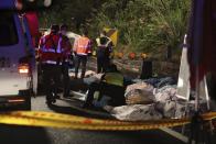 Bodies are covered as emergency services attend the scene of a crash where a bus collided with a car on a highway in Taipei, Taiwan, Monday, Feb. 13, 2017. A tour bus has flipped over on a highway near Taiwan's capital, killing over 30 people and trapping many others, officials said. (AP Photo)