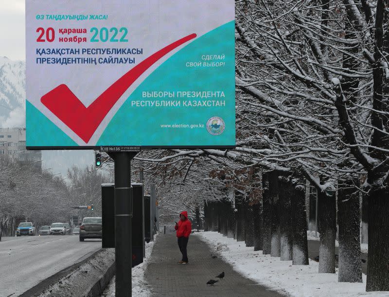 A man stands near a board informing of the upcoming presidential election in Almaty