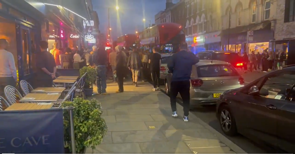 Crowd gathers outside a restaurant in Hackney following a shooting