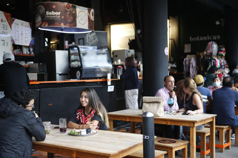 Sara Vazquez, 23, second from left, talks to Alan Salinas, 25, during a lunch in a restaurant at the Huerto Roma food plaza in Mexico City, Saturday, July 10, 2021. Mexico is entering its third wave of the coronavirus pandemic. The country's health department said Friday the growth is largely coming from infections among younger, less vulnerable people. (AP Photo/Ginnette Riquelme)