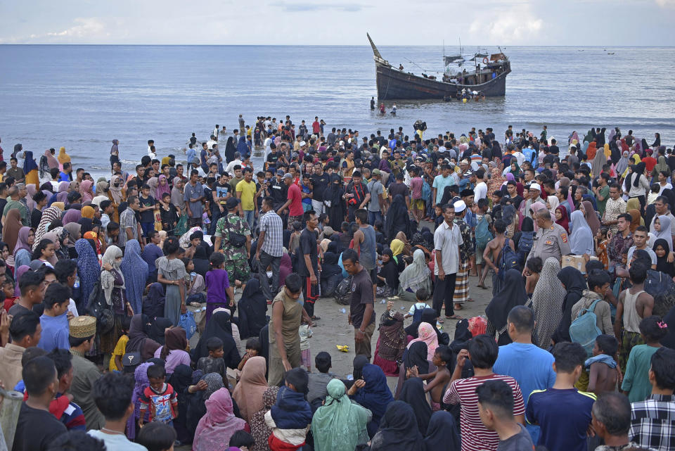 Local residents and newly-arrived ethnic Rohingya gather on the a beach in Ulee Madon, North Aceh, Indonesia, Thursday, Nov. 16, 2023. Some 240 Rohingya Muslims, including women and children, are afloat off the coast of Indonesia after two attempts to land were rejected by local residents. The boat left again a few hours later following the rejection. (AP Photo/Rahmat Mirza)