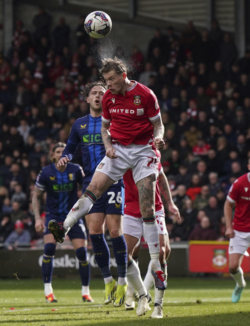 Wrexham's James McClean, top, and Mansfield Town's Will Swan challenge for the ball during the English League Two soccer match between Wrexham and Mansfield Town at the SToK Cae Ras in Wrexham, Wales, Friday, March 29, 2024. (Jacob King/PA via AP)