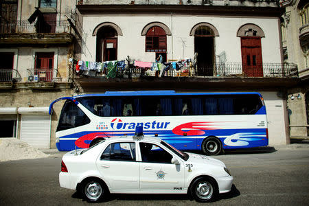 A Chinese-made Geely police car passes by a parked Yutong bus, which is also made in China, in Havana, Cuba, February 10, 2017. REUTERS/Alexandre Meneghini