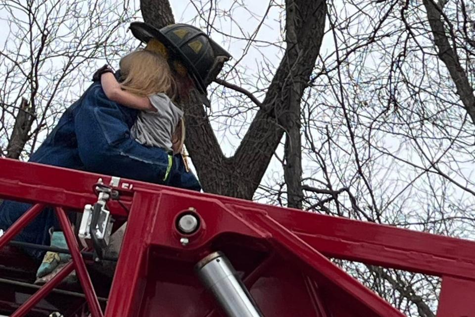 A firefighter carries a 4-year-old girl down the ladder of Truck 33 after rescuing her from 30 feet up a tree, Tuesday, Feb. 27, 2024, in Reading Township.