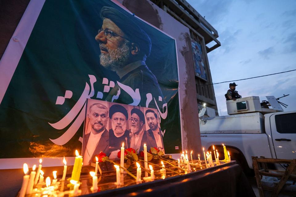 An Iraqi soldier stands guard next candles list by people paying their respects to Iran's late president Ebrahim Raisi outside the Iranian embassy in Baghdad during a condolences service on May 20, 2024 for the president and his entourage, who were killed in a helicopter crash in Iran the previous day. Iranian President Ebrahim Raisi was killed in a helicopter crash on May 19 near the Iranian-Azeri border following his return from an official visit. The victims were Raisi (on banner and bottom 2nd-L), the foreign minister Hossein Amir-Abdollahian (bottom-L), a provincial governor and an imam, along with the aircraft's three crew and two bodyguards, Iranian officials said.