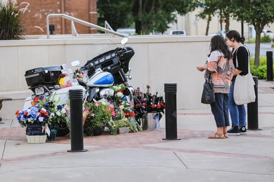 Maria and Victoria Mosburg pay their respects in July 2022 at a memorial outside the Edmond Police Department building for motorcycle officer Sgt. C.J. Nelson.