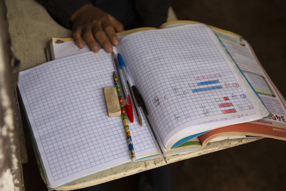 Oscar Rojas, 11, readies his notebooks, pens and pencils, as he prepares for the arrival of his teacher Gerardo Ixcoy, in Santa Cruz del Quiche, Guatemala, Wednesday, July 15, 2020. "I tried to get the kids their work sheets sending instructions via WhatsApp, but they didn't respond," said the 27-year-old teacher. "The parents told me that didn't have money to buy data packages (for their phones) and others couldn't help their children understand the instructions." (AP Photo/Moises Castillo)